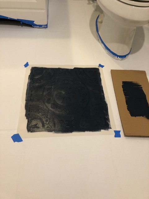 floor tile stencil taped to floor and painted in black