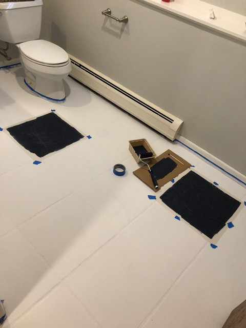  2 floor tile stencils taped to floor and painted in black