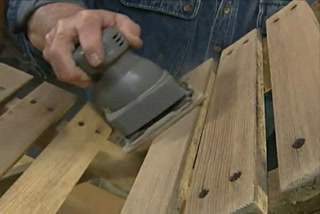 Man using orbital sander to sand and refinish an adirondack chair 