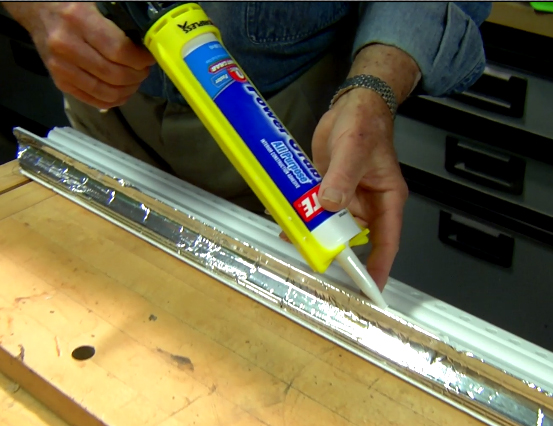Man using caulk gun to caulk molding 