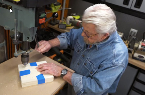 Man drilling into wood to make a rack 