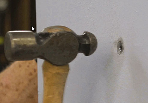 Man hammering a molly bolt below surface