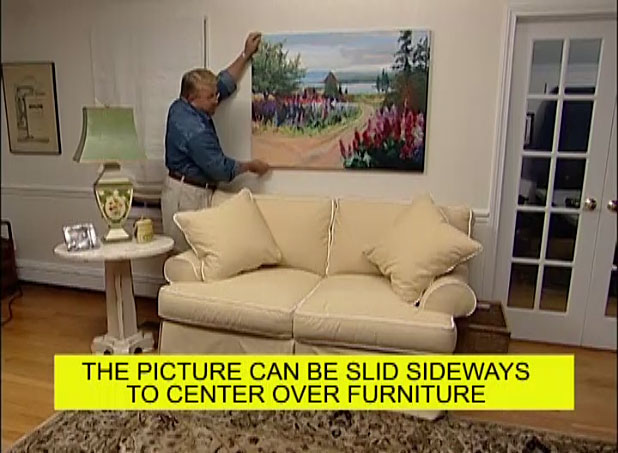 Man hanging a large picture on the wall with cleats