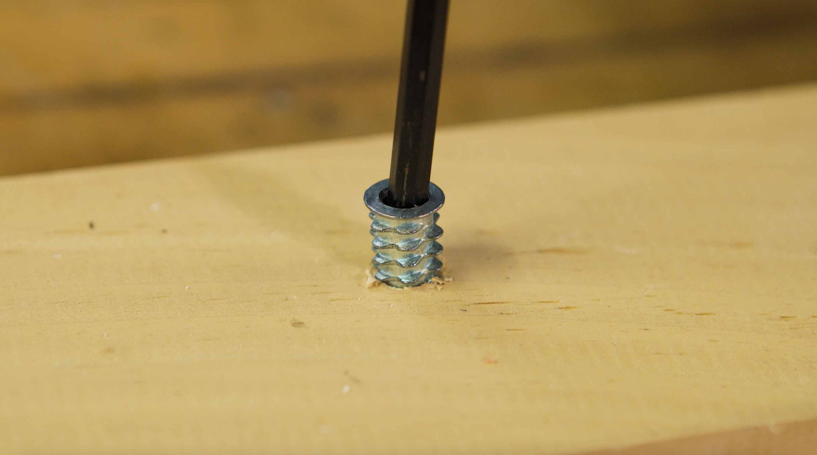 Man demonstrates how to screw a bolt into wood