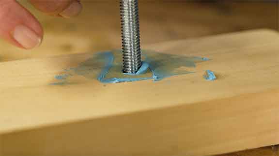 Man demonstrates how to screw a bolt into wood