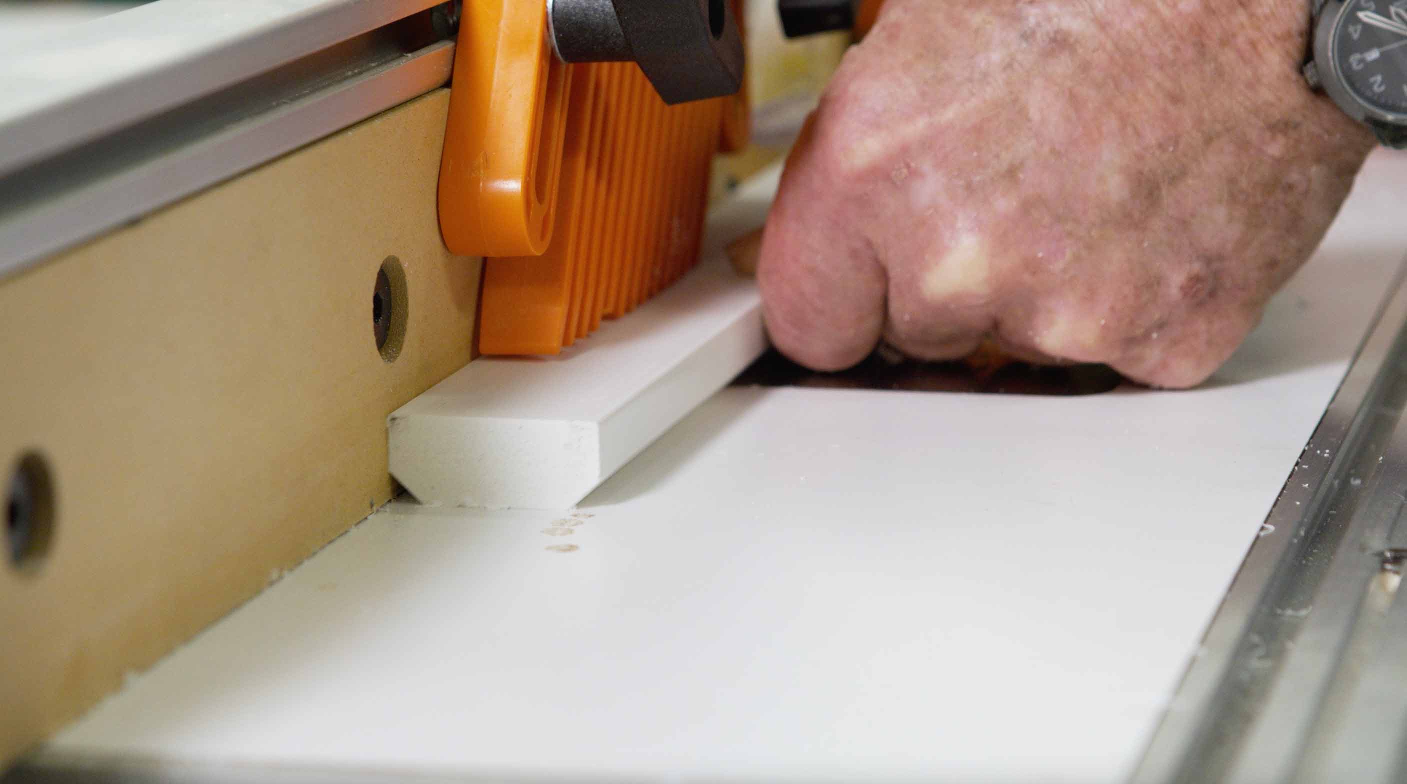 Man uses router table to bevel edge of PVC board