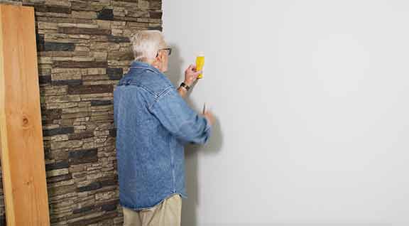 Man uses stud finder 