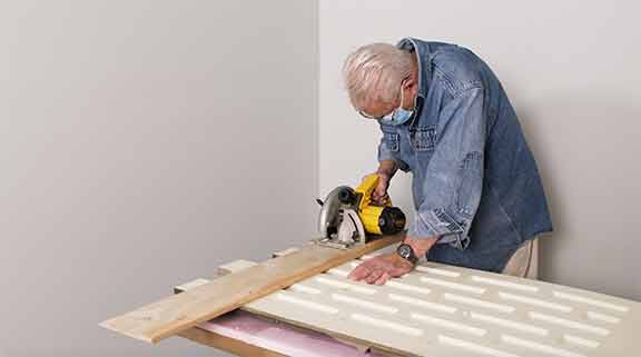 Man using a circular saw to cut faux stone panel