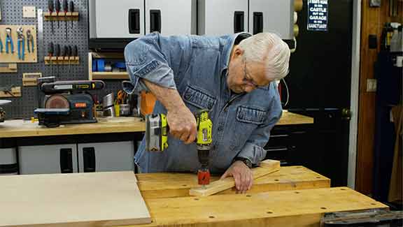 Man bores a hole with a hole saw