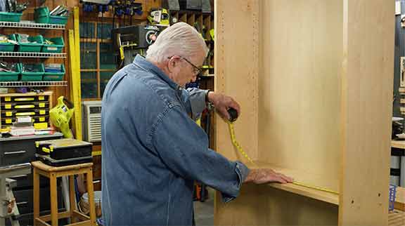 Man measuring inside of cabinet with measuring tape