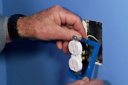 Man puts an electrical box extender behind outlet