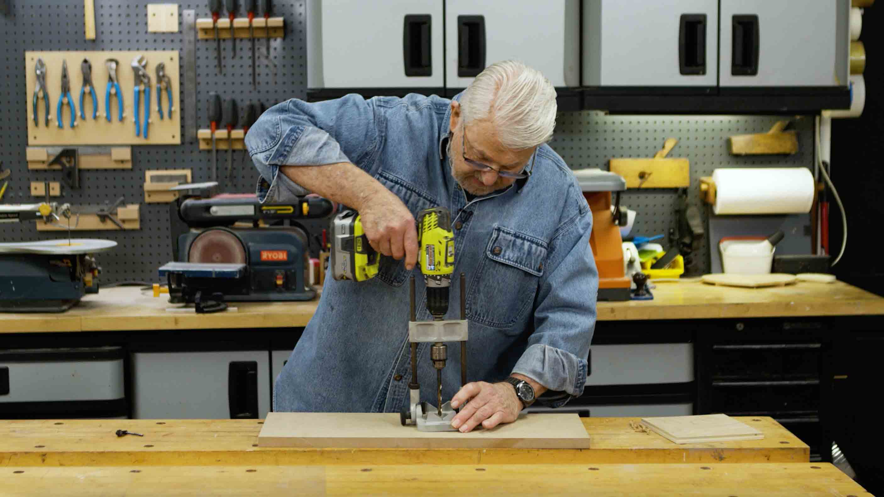 Man uses a portable drill press to drill a straight hole