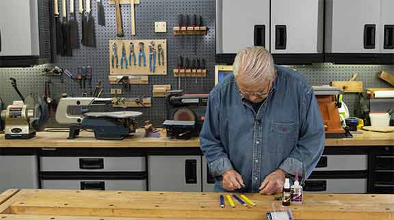 Man uses adhesive to glue magnet to a pencil