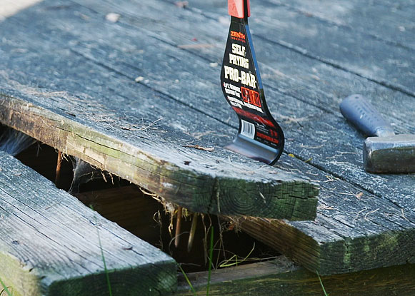 Man using the self-prying pro-bar to pry up a decking board