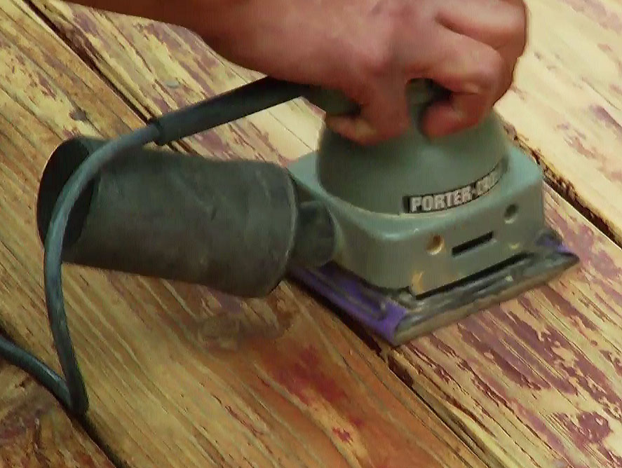 Man using orbital sander to sand and restore deck 